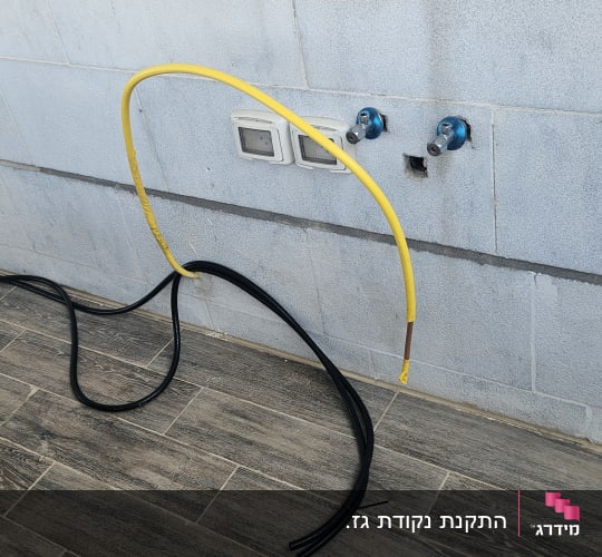 צינור גז צהוב ושני ברזים כחולים על קיר